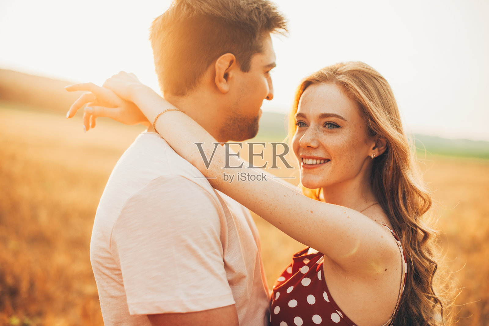 一对夫妇在麦田里拥抱的画像。有雀斑的白种人和男友约会。夕阳光照片摄影图片