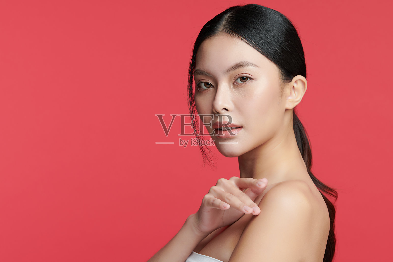 美丽年轻的亚洲女性与干净新鲜的皮肤在红色的背景，面部护理，面部治疗，美容，美容和水疗，亚洲女性肖像。照片摄影图片