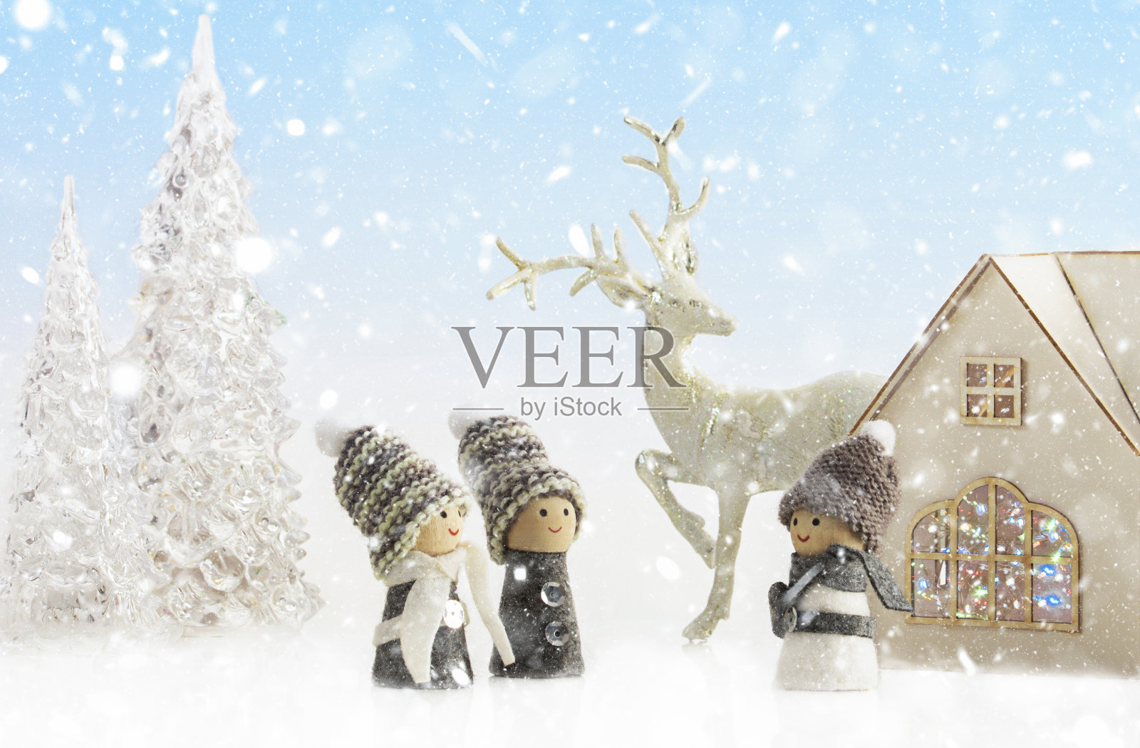 以白雪为背景的圣诞童话，家庭观念。房子里有圣诞灯、驯鹿、冰树和可爱的地精。特写镜头照片摄影图片