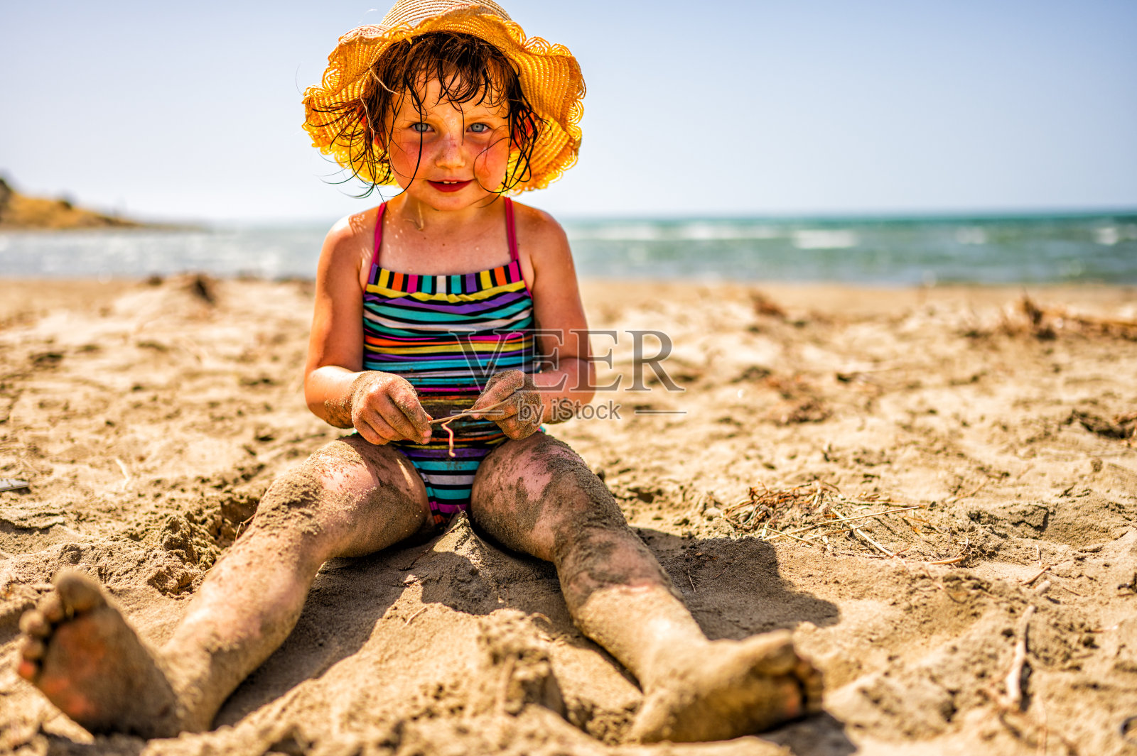 一个三岁的小女孩在沙滩上玩。照片摄影图片