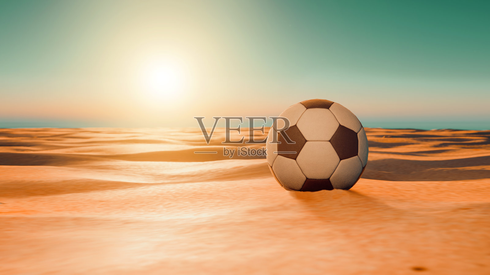 日落时分，足球躺在沙漠的沙滩上照片摄影图片