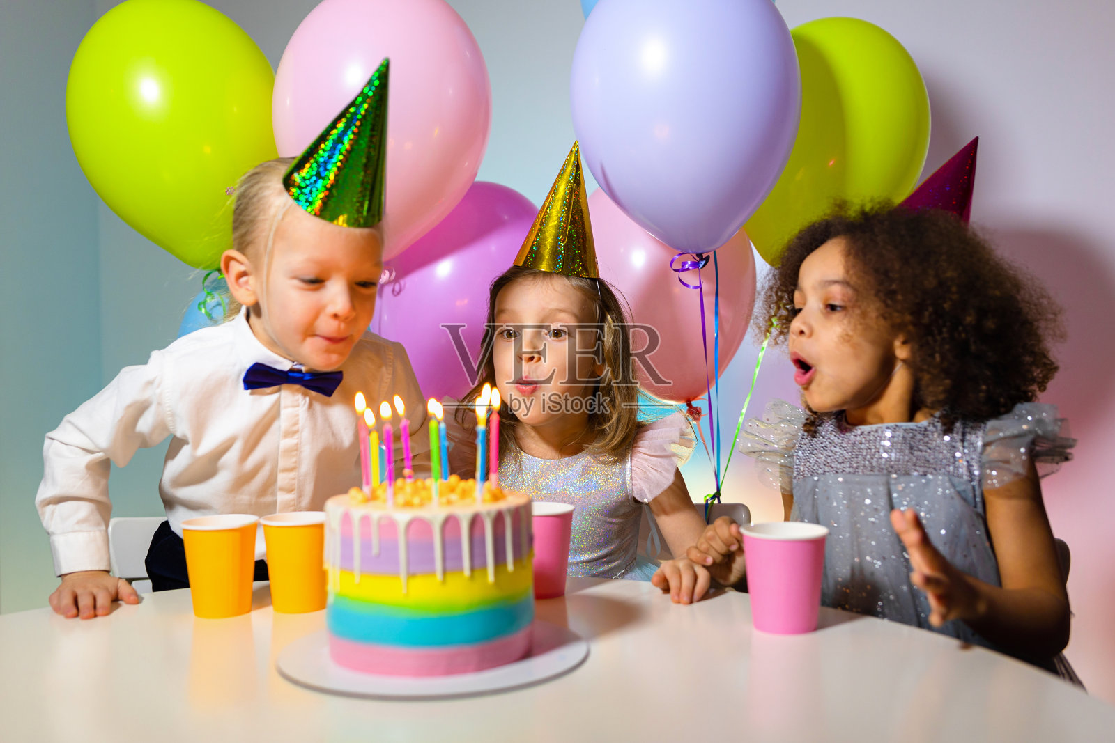 孩子们在生日聚会上吹蜡烛在蛋糕上照片摄影图片_ID:100837952-Veer图库