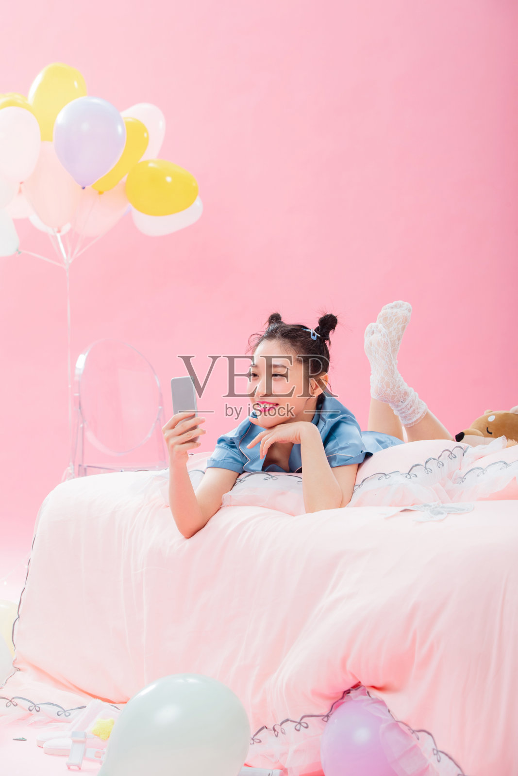 年轻女孩趴着在床上使用手机照片摄影图片