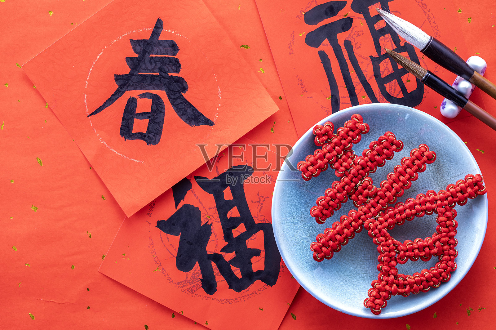 ,中国春节春联旁摆放着春字中国结和毛笔砚台照片摄影图片