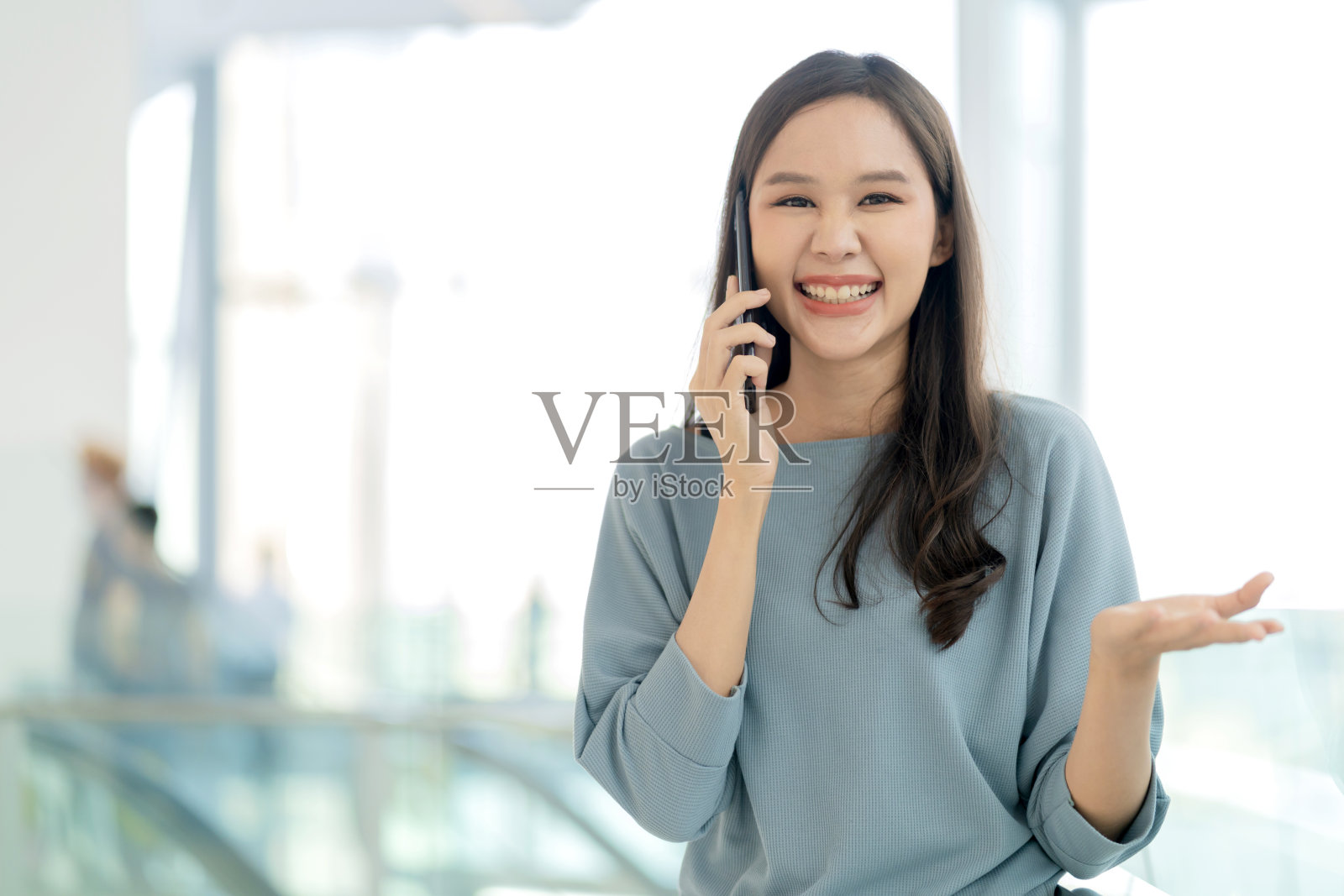 微笑的亚洲女性青少年手使用智能手机与亲密的朋友在商场百货商店或大学走廊愉快的笑微笑积极的态度情绪，年轻的亚洲女性智能手机照片摄影图片