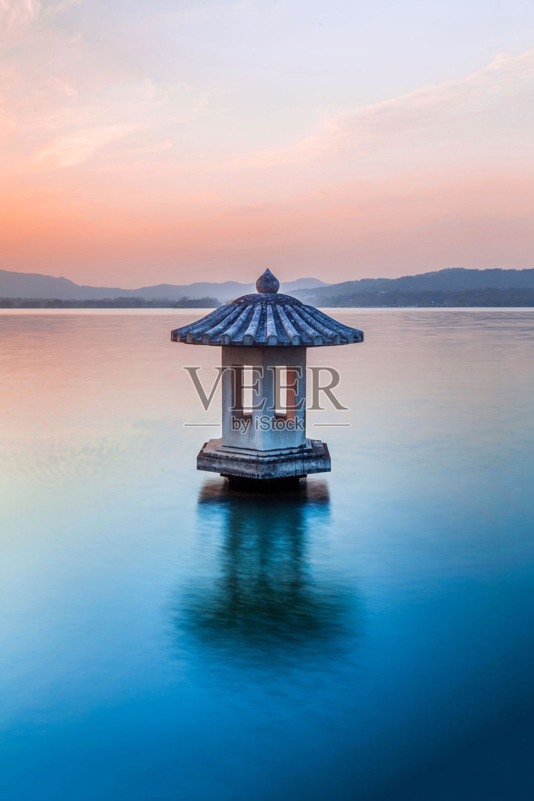 中国杭州日落时水中建筑的垂直镜头照片摄影图片