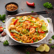 在白色的盘子里炒面条、虾和蔬菜。健康的亚洲食物摄影图片