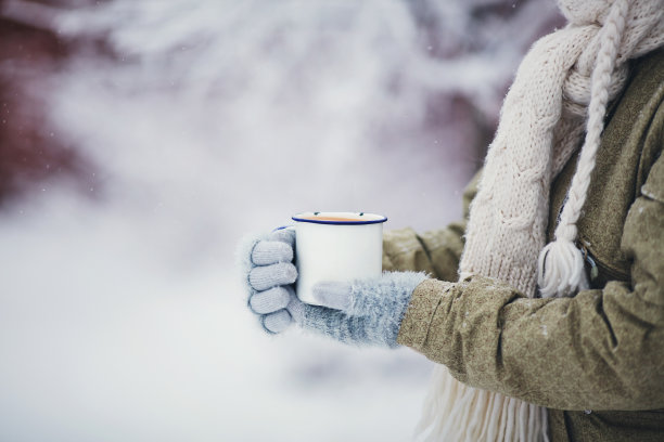 女性手捧热饮在户外的雪照片摄影图片